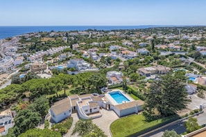 An aerial view of a residential area with houses, a swimming pool, and a clear view of the sea. - Villa Pinehill by Villa Plus (Praia do Carvoeiro)