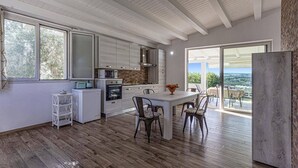 Una cocina moderna con muebles blancos, un comedor con mesa y sillas, y vistas a través de un ventanal.