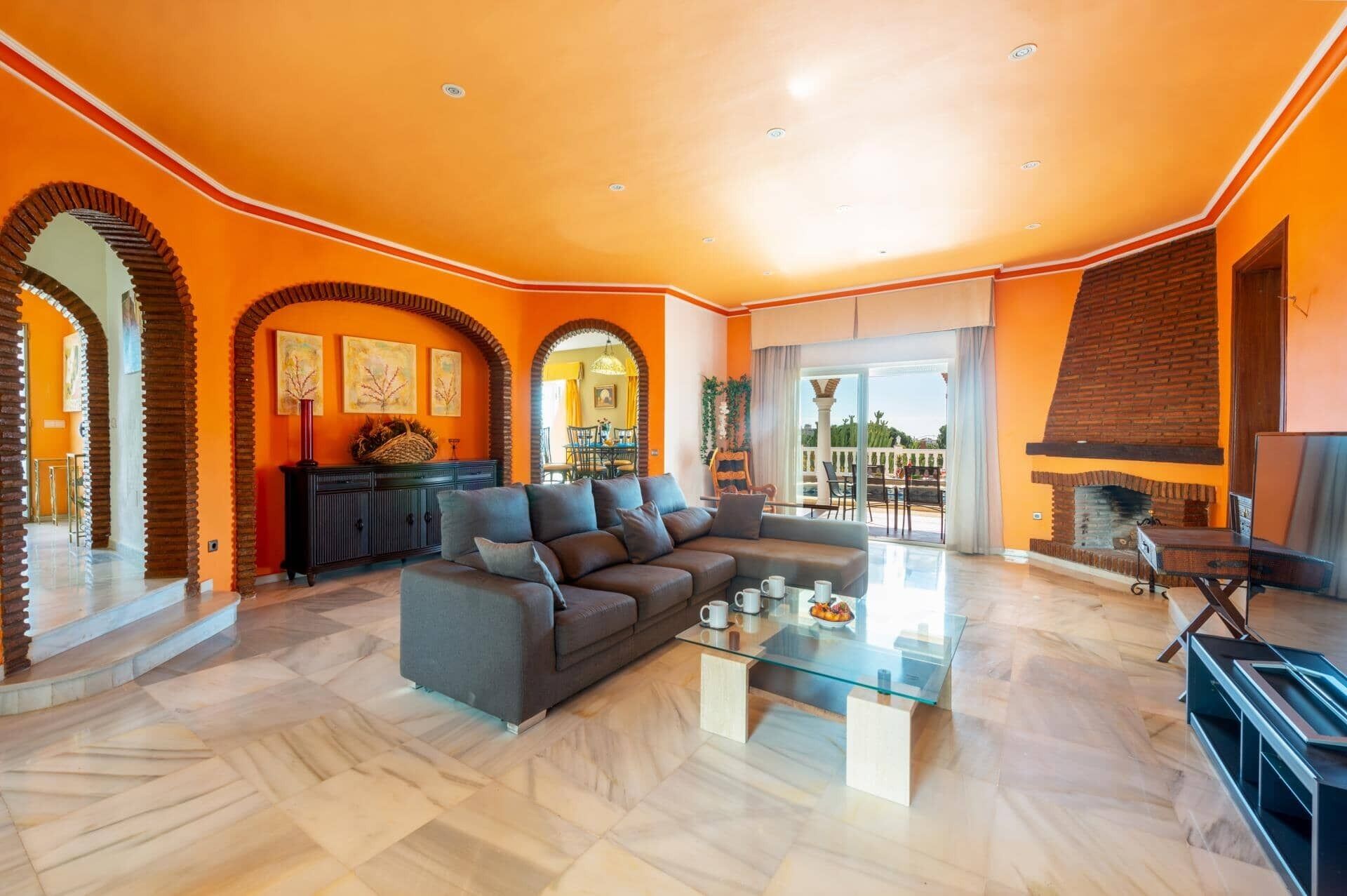 Un salón espacioso con un sofá grande, una mesa de centro de vidrio y una chimenea.