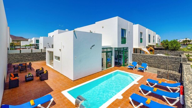 Un bâtiment moderne doté d’une piscine, d’un espace extérieur aménagé et offrant une vue dégagée sur le paysage environnant.