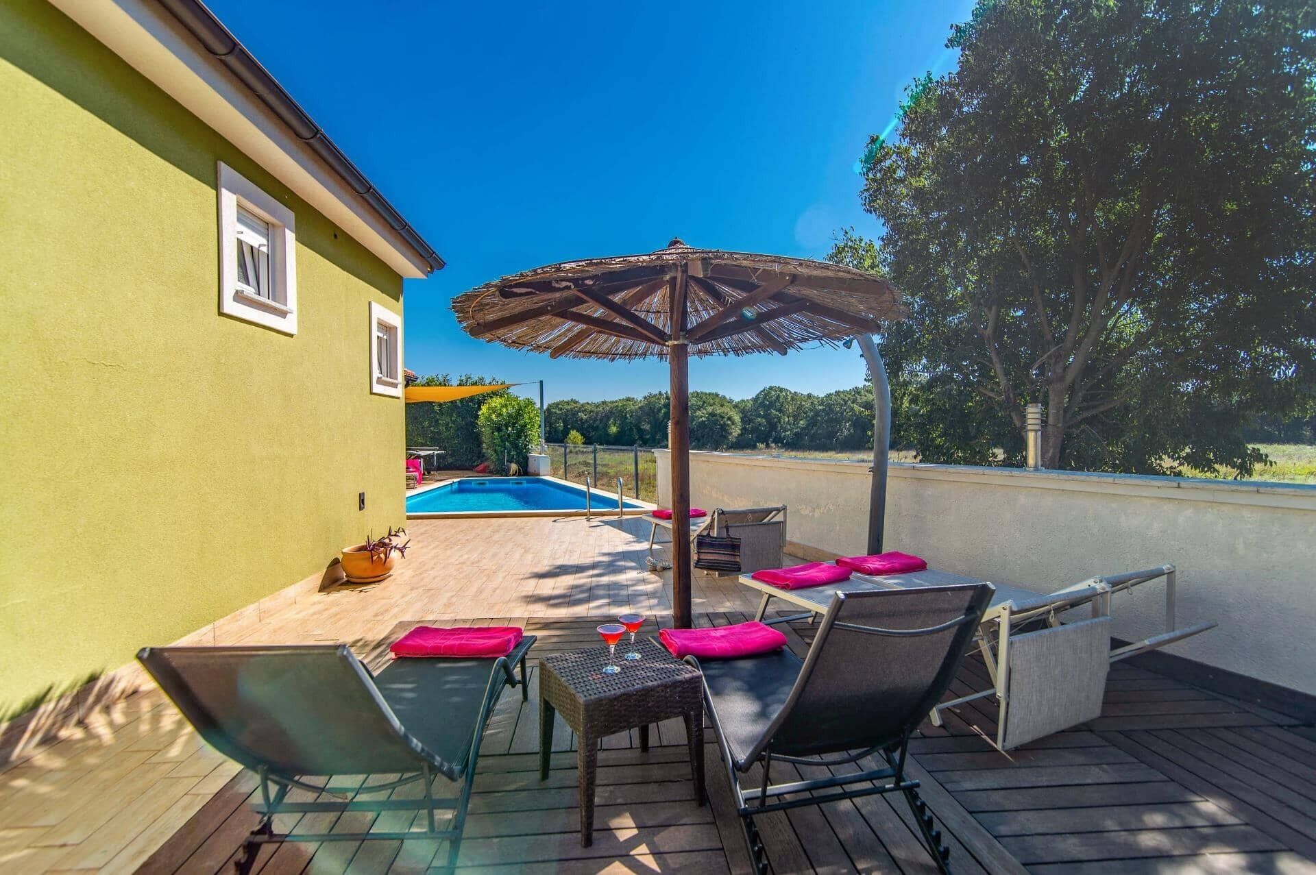 Une terrasse en bois avec une piscine, un espace salon extérieur et une pergola.
