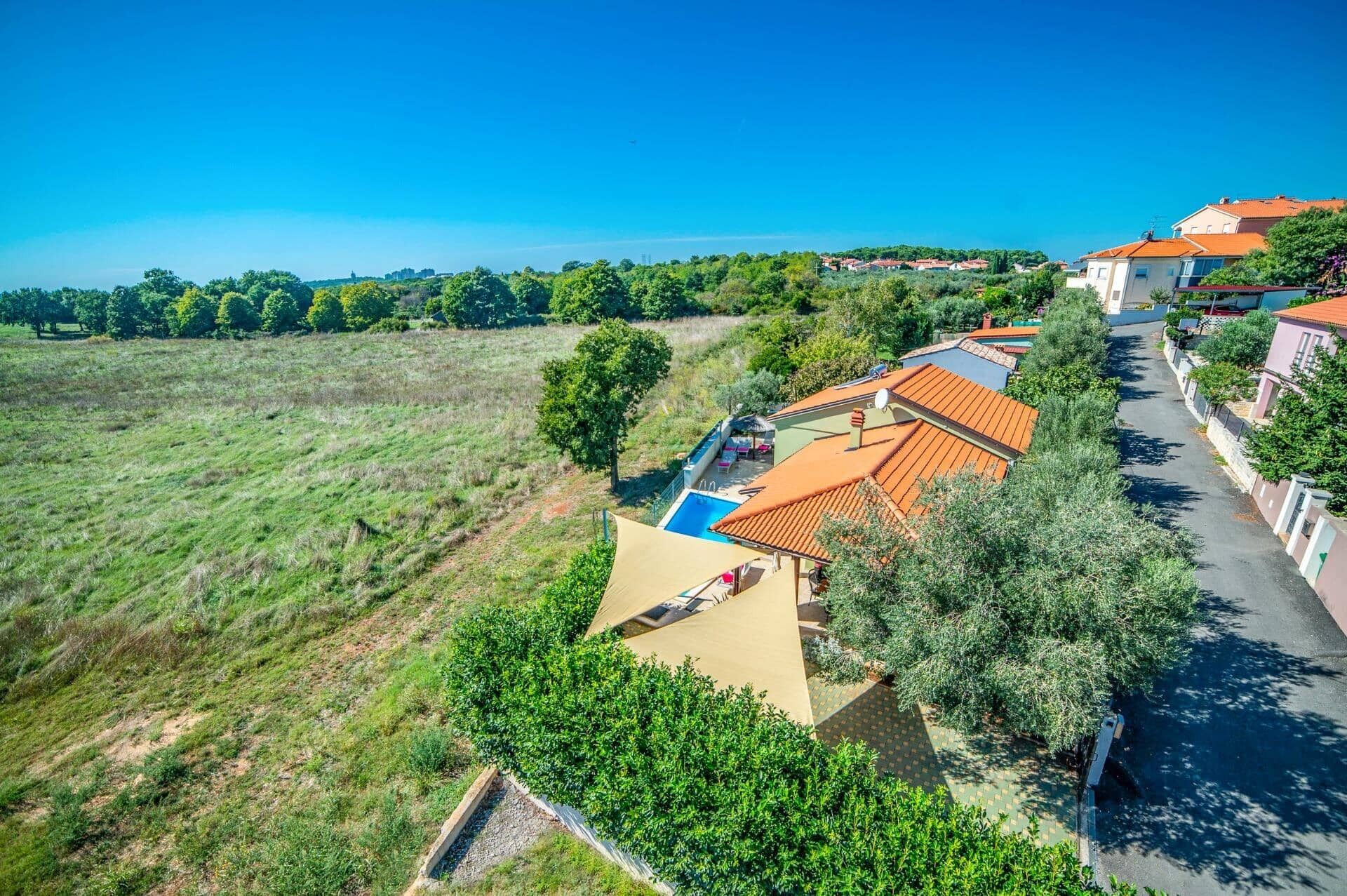 A residential area with houses, a swimming pool, and a large open field.