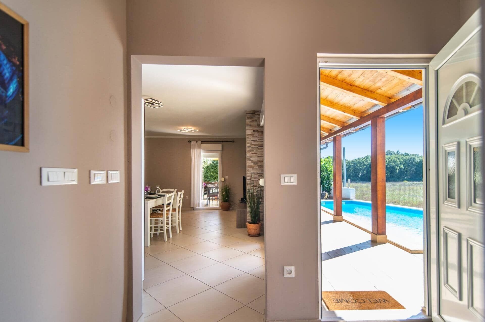 A hallway leading to a dining area and a poolside area with a view of the pool.
