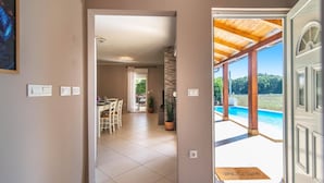 Un couloir mène à une salle à manger et à un espace aménagé près de la piscine, offrant une vue sur celle-ci.
