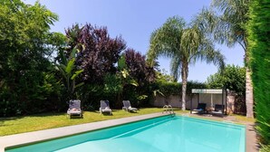 A swimming pool with lounge chairs and a covered seating area.