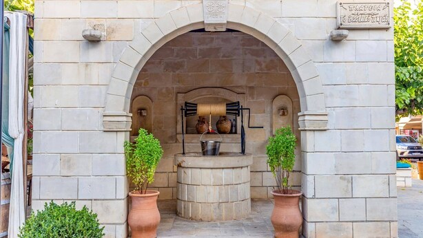 A stone archway with a small, rustic outdoor kitchen setup, including a wood-fired stove and potted plants.