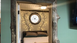 Ein Schlafzimmer mit einem Bett, einem Holzkopfende, einer runden Wanddekoration und einem kleinen Rundtisch.