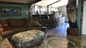 Ein gemütliches Wohnzimmer mit Kamin aus Stein, Holzboden und einem großen Fenster.