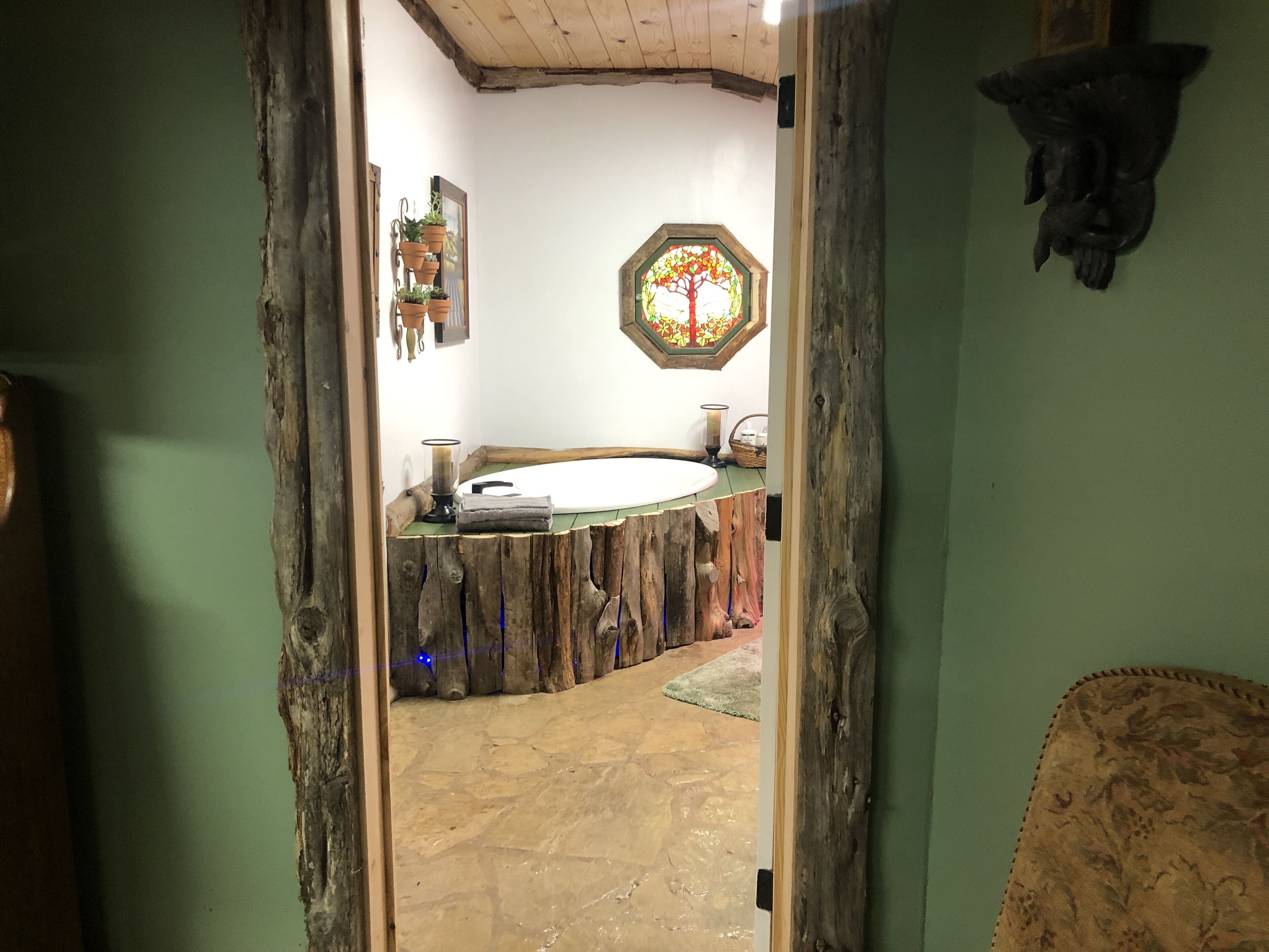 A rustic bathroom with a wooden vanity, a stained glass window, and a stone floor.