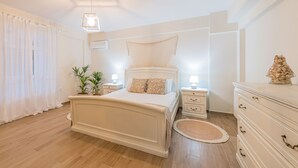 A bedroom with a bed, bedside tables, a dresser, and a ceiling light fixture. - Villa Zante Pnoe by Villa Plus (Pantokratoras)