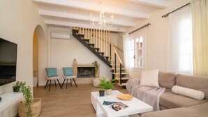 A living room with a fireplace, a staircase, a sofa, and a coffee table. - Villa Zante Pnoe by Villa Plus (Pantokratoras)