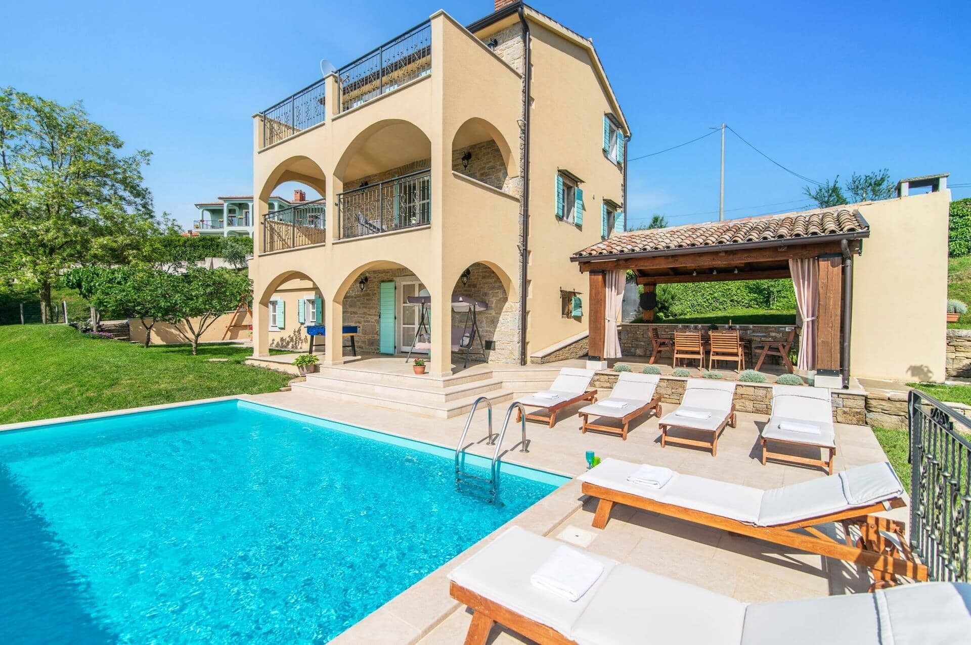 A two-story building with a swimming pool, outdoor seating, and a pergola.