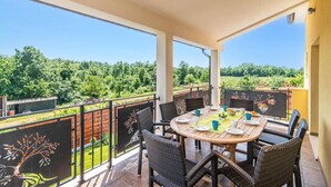 A balcony with a round table and wicker chairs, overlooking a vineyard. - Villa Zupan by Villa Plus (Barici)