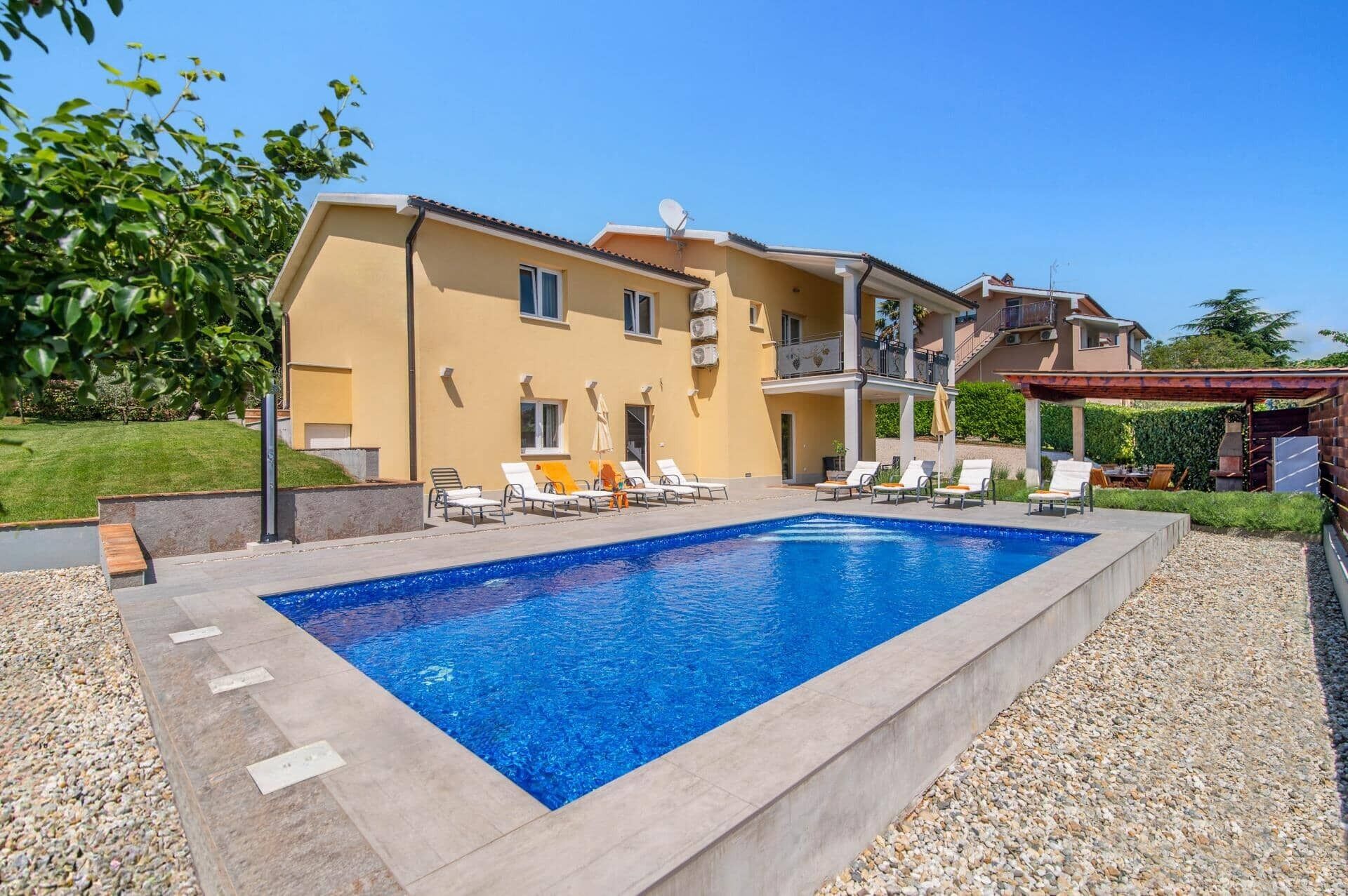 A swimming pool with lounge chairs and a building with balconies.