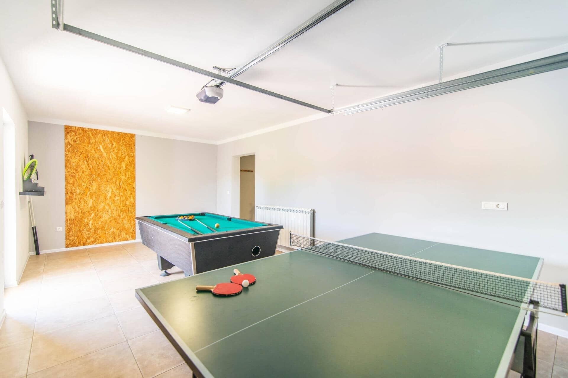 A room with a pool table, a ping pong table, and a billiards table.