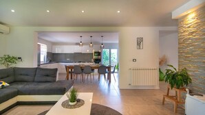 A modern living room with a sofa, a coffee table, and a dining area with chairs and a table. - Villa Zupan by Villa Plus (Barici)