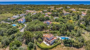 Vista aérea de uma área residencial costeira com casas, uma piscina e uma vista clara do mar.