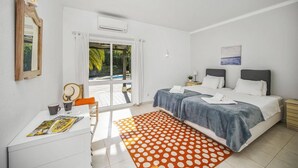 Quarto com duas camas, uma escrivaninha, uma cadeira, uma janela e vista para o exterior.