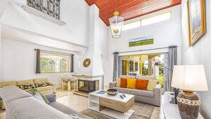 Amplia sala de estar con chimenea, comedor y vistas al exterior.
