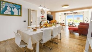 Un comedor con una mesa dispuesta para cuatro, un televisor y vistas al exterior.