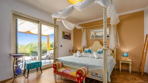 Un dormitorio con cama de dos plazas, un banco, una mesita y vistas al exterior.