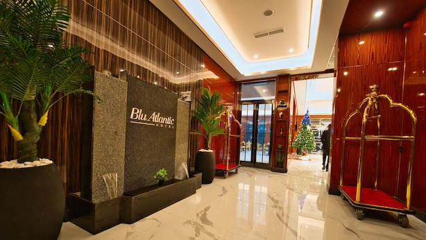 En hotellobby med gulv af poleret marmor, en receptionsdisk og et juletræ.