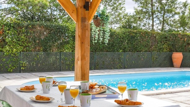 Colazione a bordo piscina con croissant, succo d'arancia e tazze di caffè.