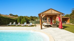 Area piscina con lettini, un gazebo in legno e un cielo azzurro.