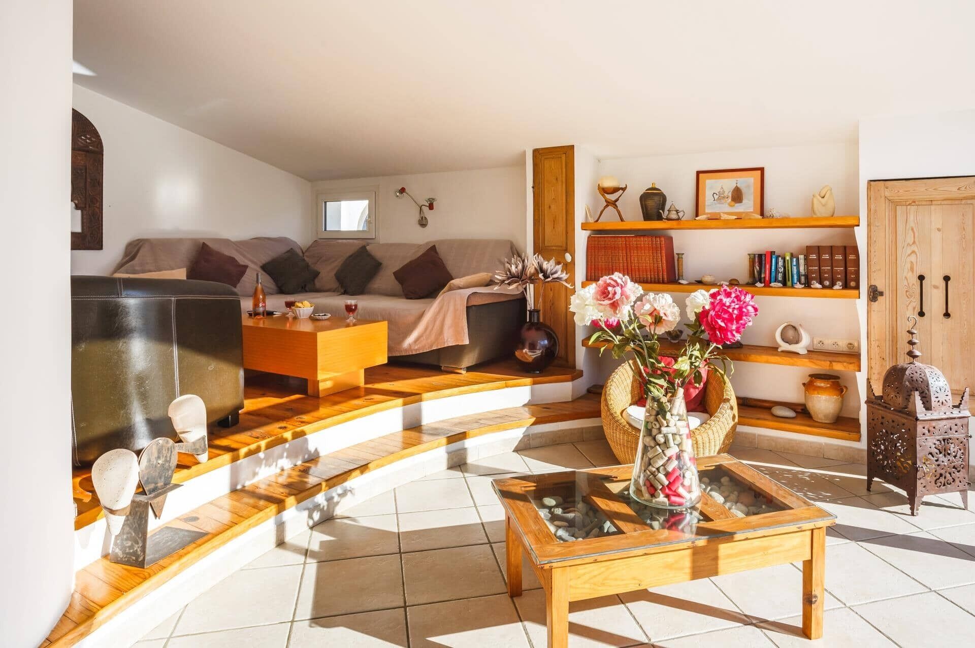 A living room with a sofa, coffee table, and shelves with books and decorative items.