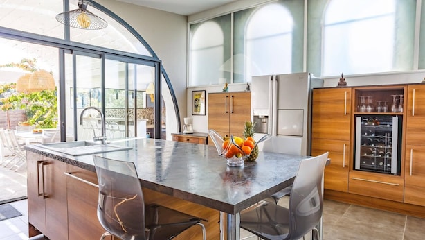 A modern kitchen with a large island, wooden cabinets, and a refrigerator. - Villa Saffron by Villa Plus (Villedaigne)