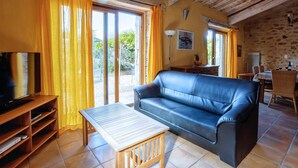 A living room with a leather sofa, a wooden coffee table, and a TV on a wooden stand. - Villa Fraisse by Villa Plus (Fraissé-des-Corbières)