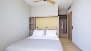 A hotel room with a bed, a ceiling fan, a wardrobe, and a small shelf with books. - Villa Lavender Bloom by Villa Plus (Lefkada)