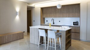 A modern kitchen with a central island, bar stools, a microwave, and a sink. - Villa Lavender Bloom by Villa Plus (Lefkada)