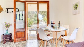 A dining area with a round table, white chairs, and a view of the outdoors.