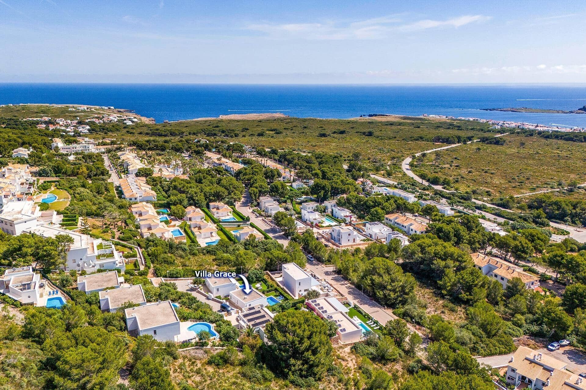 Vista aérea de una zona residencial costera con villas, incluyendo Villa Grace, rodeada de vegetación y el mar.
