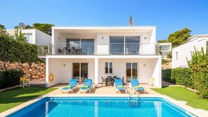A two-story building with a swimming pool, outdoor seating, and a balcony. - Villa Grace by Villa Plus (Es Mercadal)