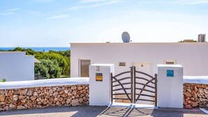 A villa with a stone wall entrance, a gate, and a satellite dish. - Villa Grace by Villa Plus (Es Mercadal)