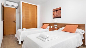 A hotel room with two beds, a wooden wardrobe, a wall-mounted air conditioner, and a painting. - Villa Grace by Villa Plus (Es Mercadal)