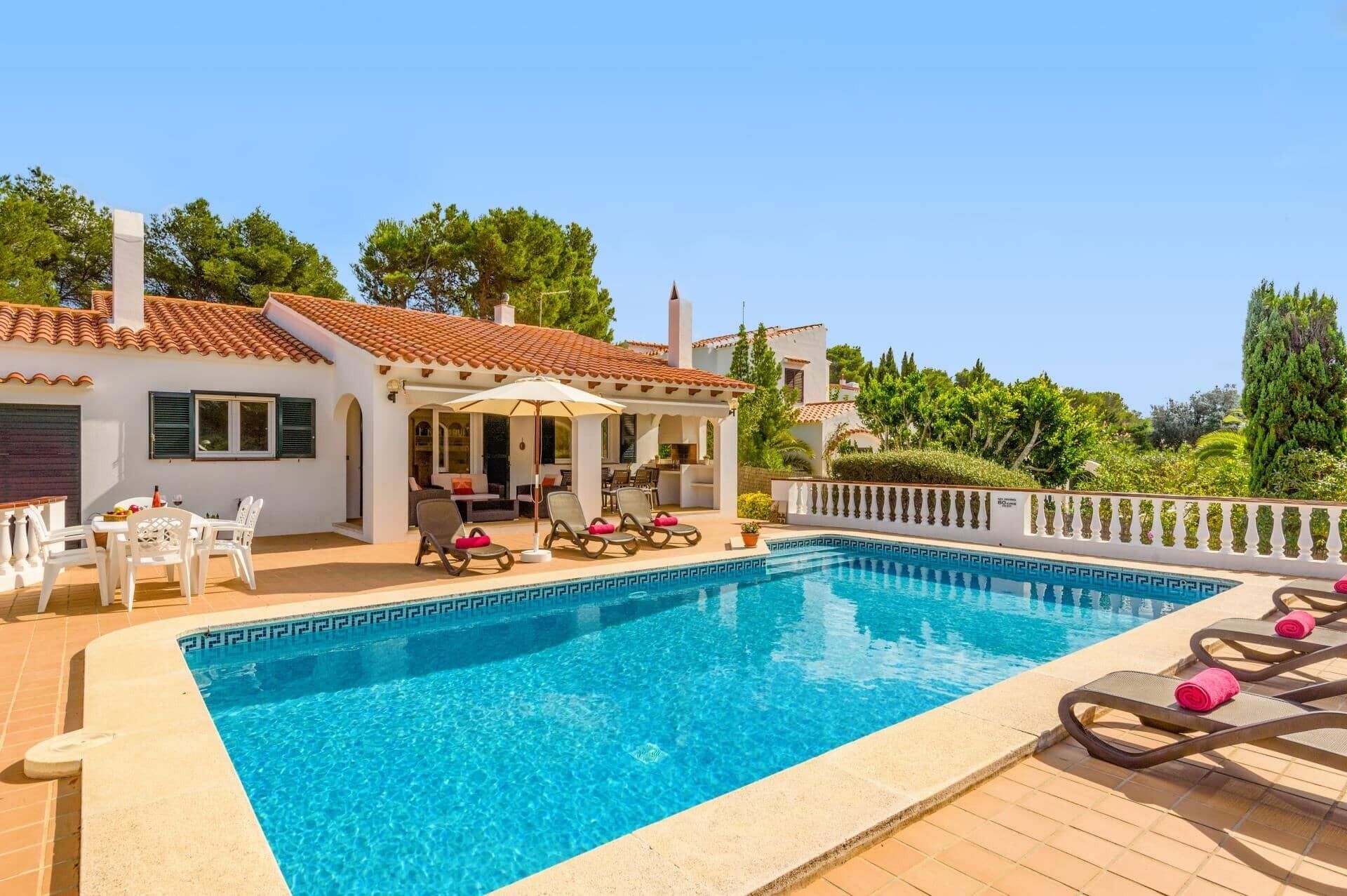 A poolside area with a pool, lounge chairs, and a patio with outdoor furniture.
