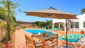 Un espace aménagé au bord de la piscine, avec une table et des chaises, des fauteuils de relaxation et une pergola.