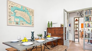 Un coin repas avec une longue table dressée pour quatre personnes, un banc en bois et une carte accrochée au mur.