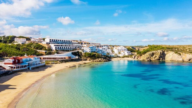 Une ville côtière aux bâtiments blancs, dotée d’une plage de sable fin et bordée d’eaux d’un bleu limpide.