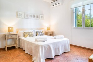 A bedroom with a bed, two bedside tables, a window, and wall art.