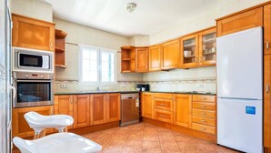 Une cuisine avec des meubles de rangement en bois, un réfrigérateur blanc, un four à micro-ondes, un four traditionnel et un évier.