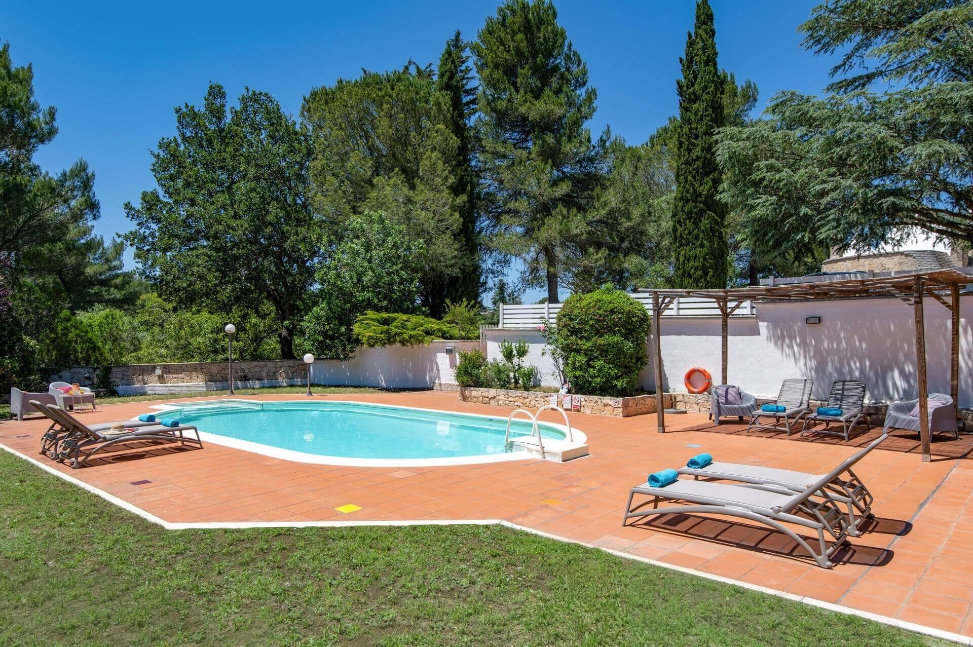 Une piscine avec des chaises longues et une pergola.