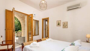 Une chambre d’hôtel comprenant un lit, une chaise, une table et une porte donnant sur un espace extérieur.