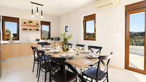 Cocina moderna con comedor, que incluye una isla grande, sillas negras y vistas al campo.