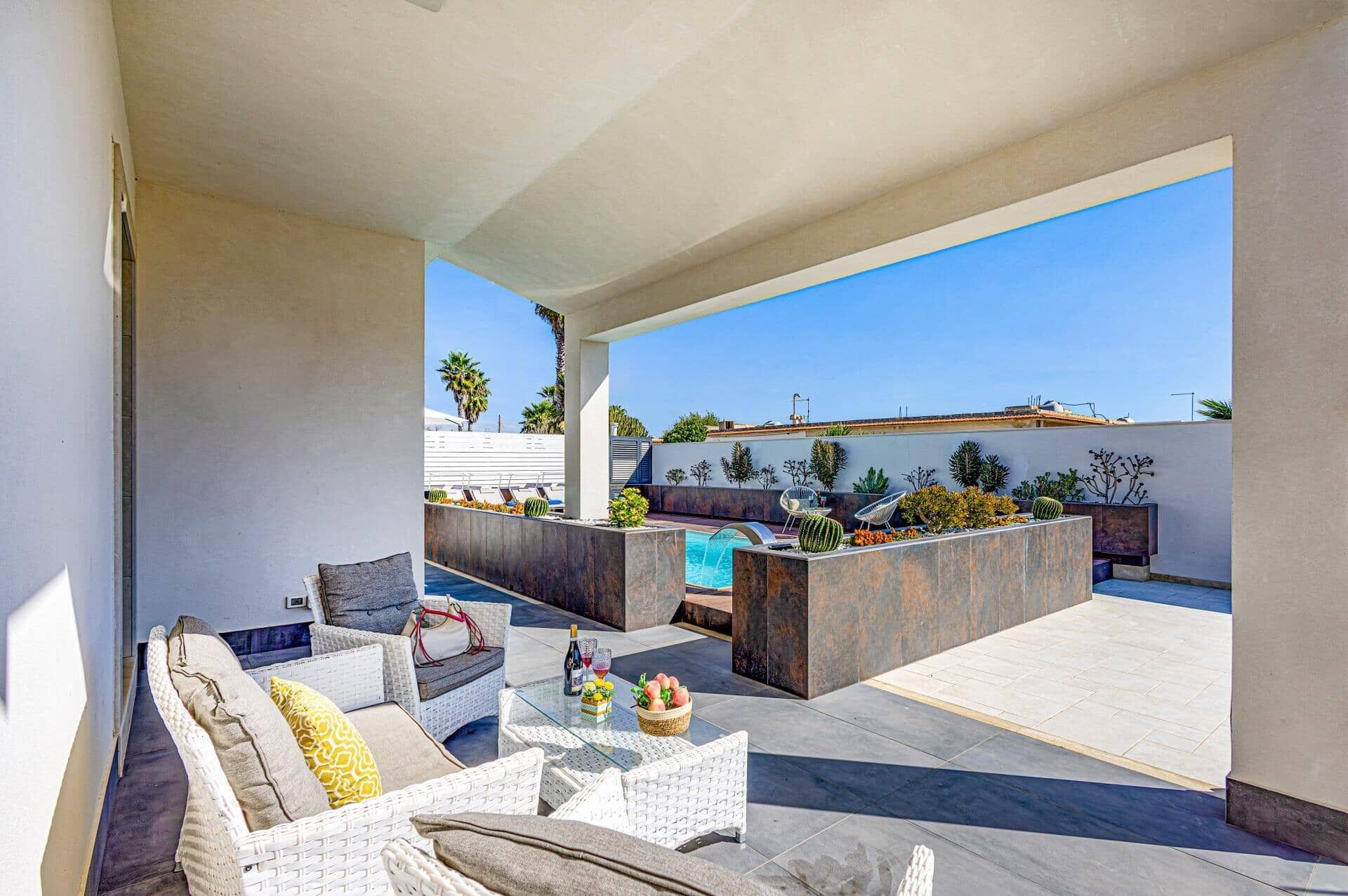 Eine Dachterrasse mit Sitzgelegenheiten im Freien, einem Pool und Blick auf Palmen.