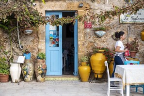 A rustic building with a blue door, potted plants, and a sign indicating a Michelin rating.