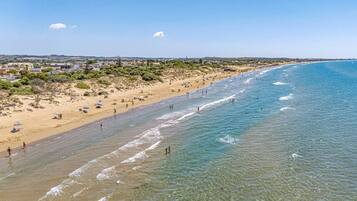 Une plage avec une eau claire, un rivage sablonneux et quelques parasols.